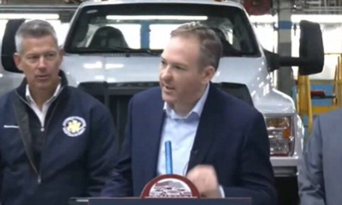 Lee Zeldin speaking at Ford plant with officials in background