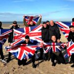 Small group waving flags on a French beach near Calais with police nearby