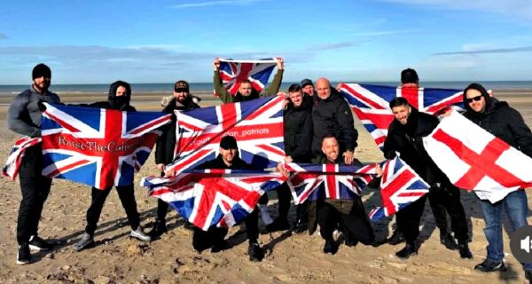 Small group waving flags on a French beach near Calais with police nearby