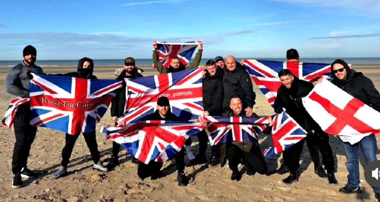 Small group waving flags on a French beach near Calais with police nearby