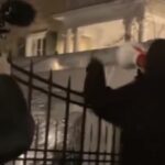 Protesters outside Gracie Mansion at night with megaphone