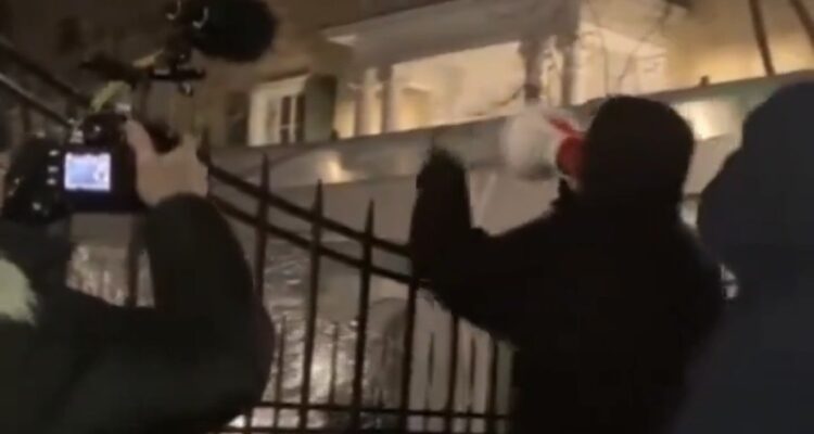 Protesters outside Gracie Mansion at night with megaphone