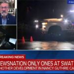 Law enforcement vehicles and SWAT team in a residential Tucson neighborhood at night.