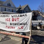 Roundabout-style barricade on Cedar Ave with people and a 'No Honking' sign