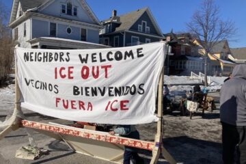Roundabout-style barricade on Cedar Ave with people and a 'No Honking' sign