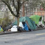 City street in Portland with boarded storefronts and tent encampments