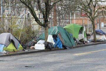 City street in Portland with boarded storefronts and tent encampments