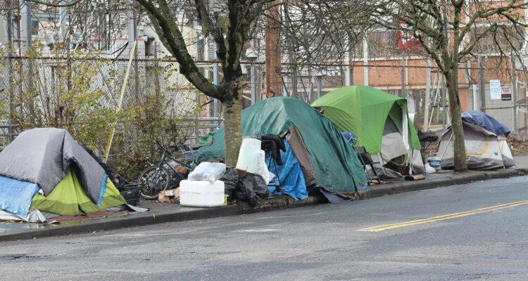 City street in Portland with boarded storefronts and tent encampments