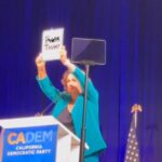 Katie Porter holding sign reading 'F-ck Trump.' on stage