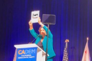 Katie Porter holding sign reading 'F-ck Trump.' on stage