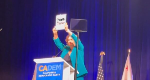 Katie Porter holding sign reading 'F-ck Trump.' on stage