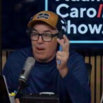 Adam Carolla speaking into a microphone on his podcast