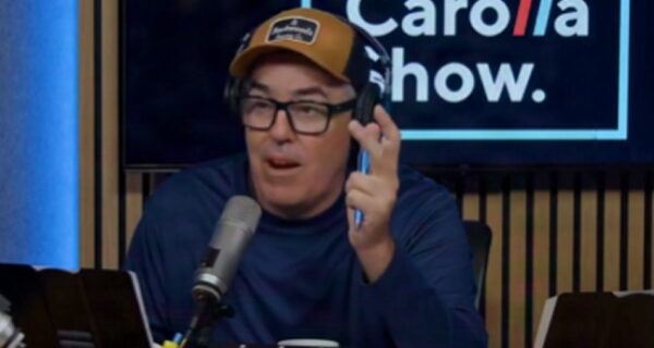 Adam Carolla speaking into a microphone on his podcast