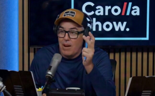 Adam Carolla speaking into a microphone on his podcast