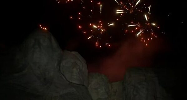 Mount Rushmore at dusk with fireworks in the sky
