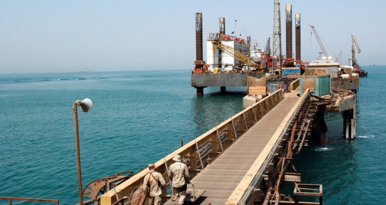 Oil rigs silhouetted against a fiery sky representing rising oil prices