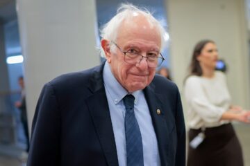 Bernie Sanders speaking at a campaign event with a Netflix logo nearby