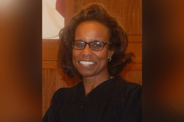 Federal judge ruling on an election case with a voting sign in the background