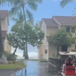 A massive wave crashes over an oceanfront condo roof in Hawaii and tears shingles loose.