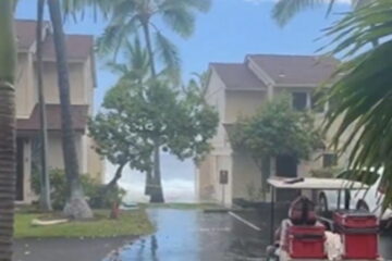 A massive wave crashes over an oceanfront condo roof in Hawaii and tears shingles loose.
