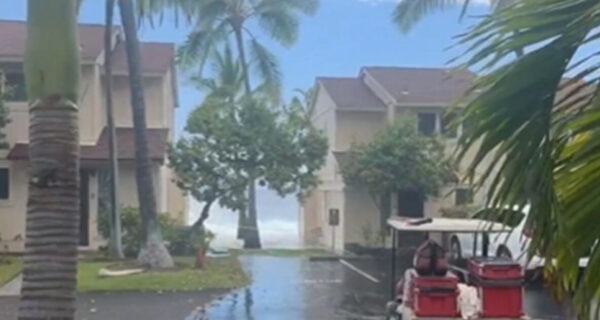 A massive wave crashes over an oceanfront condo roof in Hawaii and tears shingles loose.
