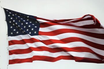 American flags near a Massachusetts beach community with dunes in the background