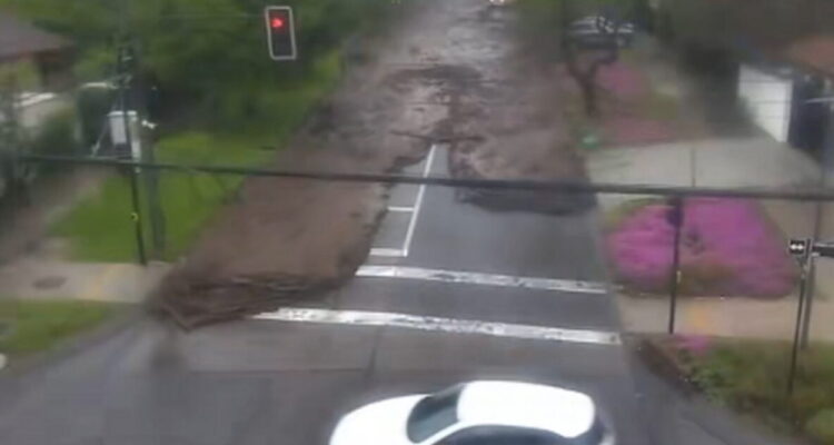 Flash floodwaters sweep cars through a street in Santiago, Chile, after heavy rain.