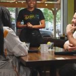 Abdul El-Sayed sits with a Black woman at a restaurant during a voter outreach video